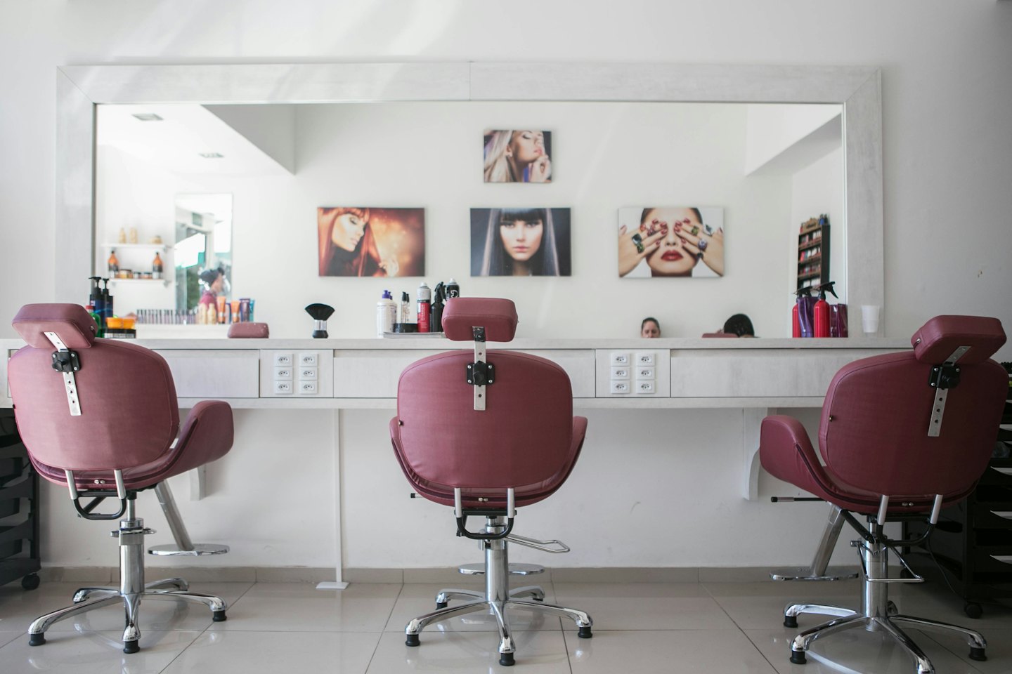 Modern salon chairs at a white counter with beauty products.