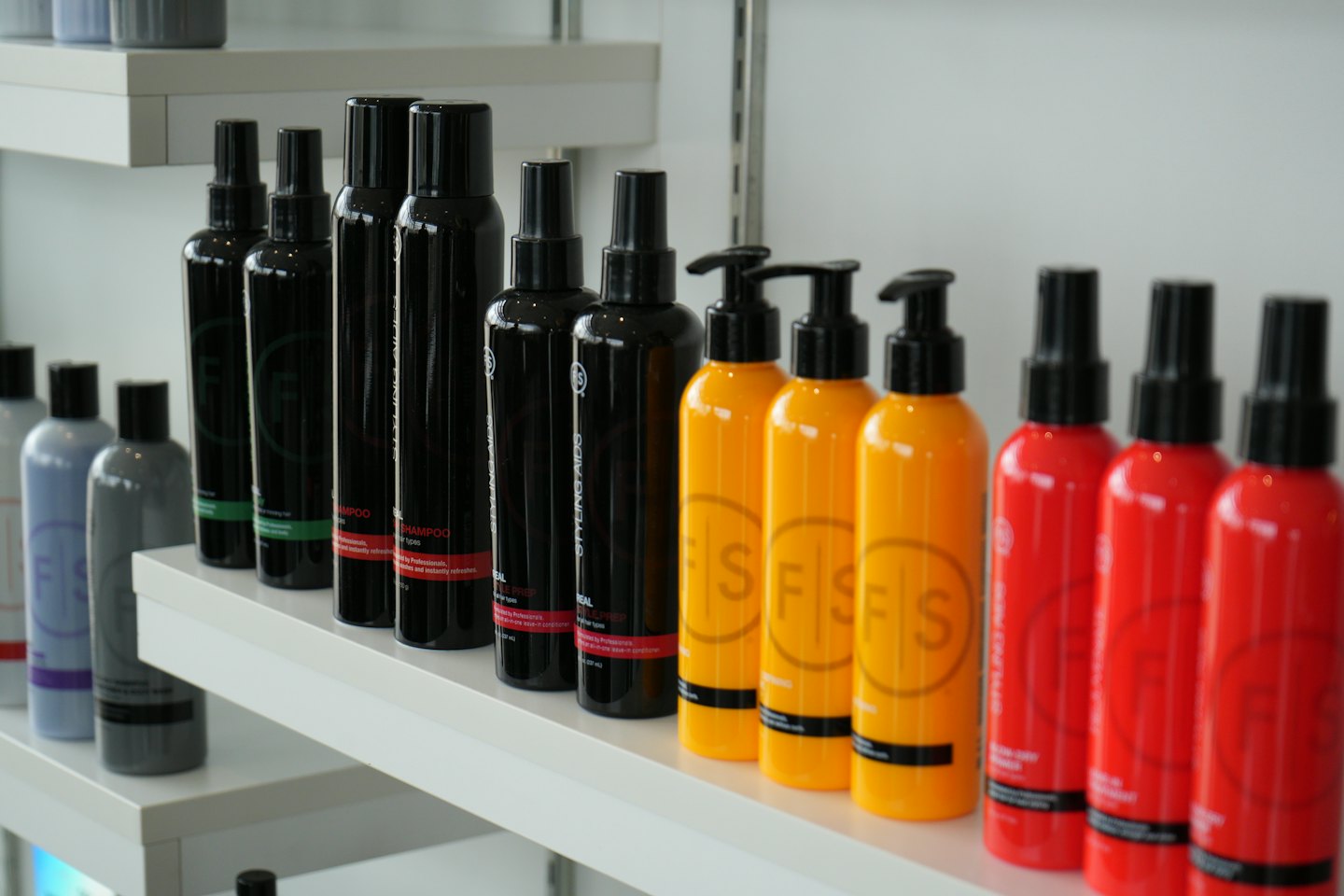 Colorful shampoo and styling bottles arranged neatly on white shelves.